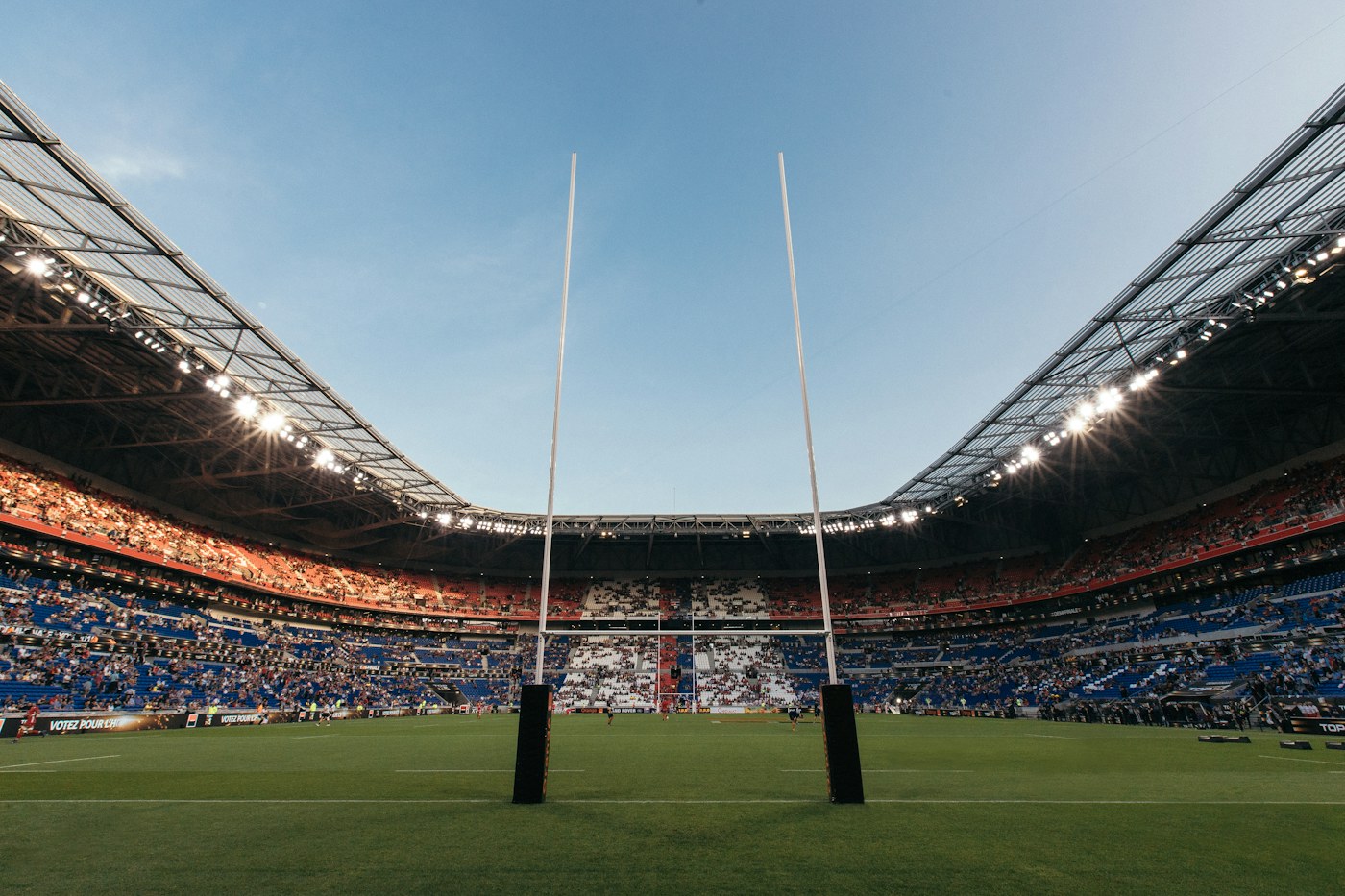 Rugby goal posts on a green field inside a large crowded stadium